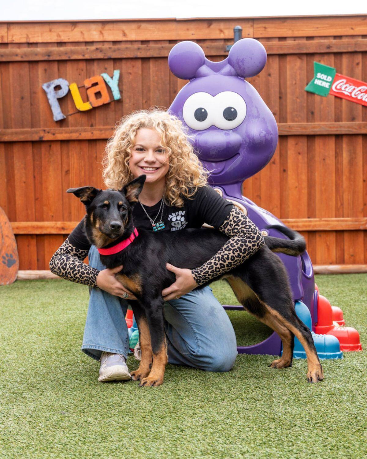 Taylor Neal kneeling with a pup in the play yard